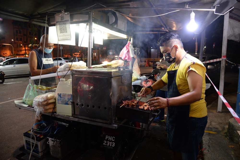 Tan Boon grilling the orders for customers during his night session in Air Itam. 
