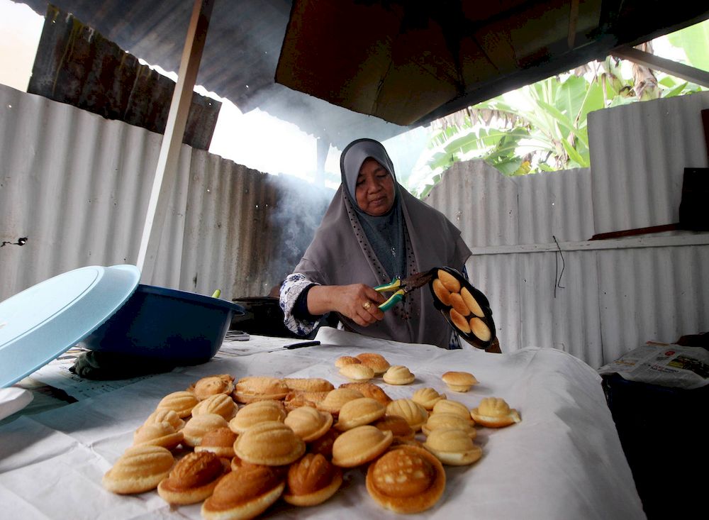 Rokiah Kulop Malodin, or more affectionately known as Mak Cik Kiah bakes kuih bahulu cakes using firewood and coconut fibre in Kampung Guar, Manong, Kuala Kangsar, April 19, 2021. u00e2u20acu201d Bernama pic