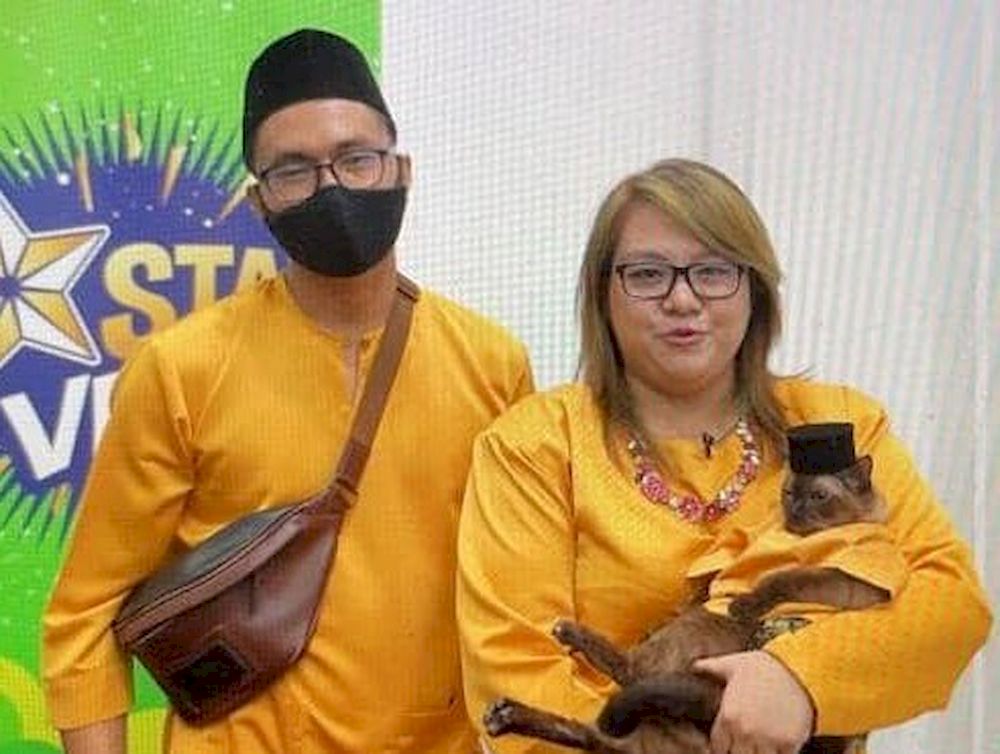 Founder of Meowkushop Mohammad Affan Aizat Anuar (left) and Raja Nur Alya together with a cat wearing the songkok. — Picture via Raja Nur Alya