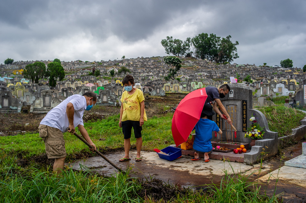 Family members clean and pray at the graves of their ancestors as a sign of respect and to honour their deceased relatives during the Qing Ming festival at the Kwong Tong Chinese Cemetery in Kuala Lumpur April 4, 2021. — Picture by Shafwan Zaidon