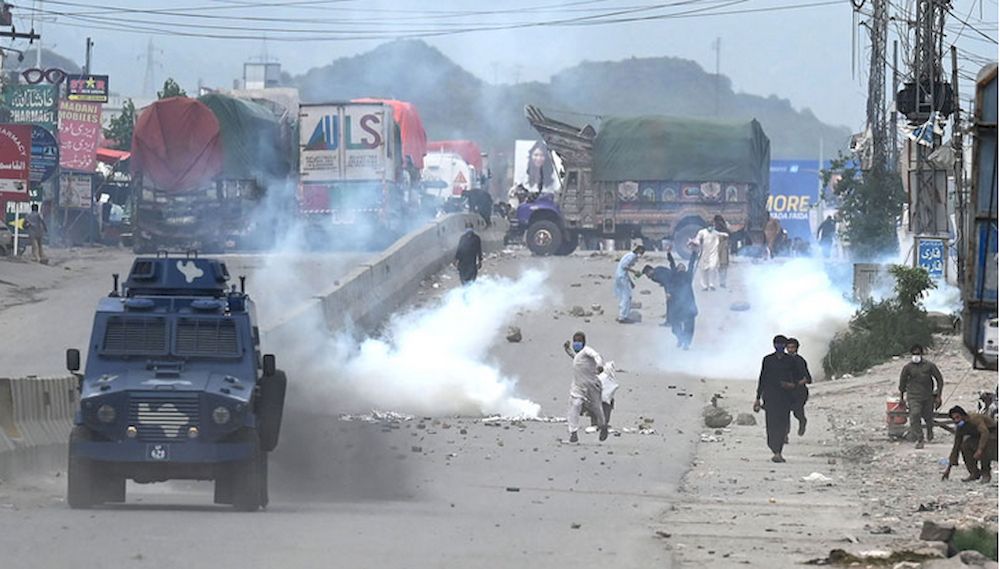 Supporters of Tehreek-e-Labbaik Pakistan party throw stones over the police armoured vehicle during a protest against the arrest of their leader as he was demanding the expulsion of the French ambassador over depictions of Prophet Muhammad, in Islamabad, 