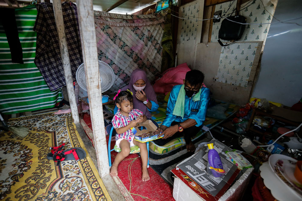 Effandy Abd Rahim and his wife Salbilla Supriyadi with their daughter Nuur Zulaieca sitting in their makeshift bedroom in a storeroom after their old house caught fire here at Lorong Sempadan Dua, Ayer Itam, April 19, 2021. u00e2u20acu201d Picture by Sayuti Zainudin