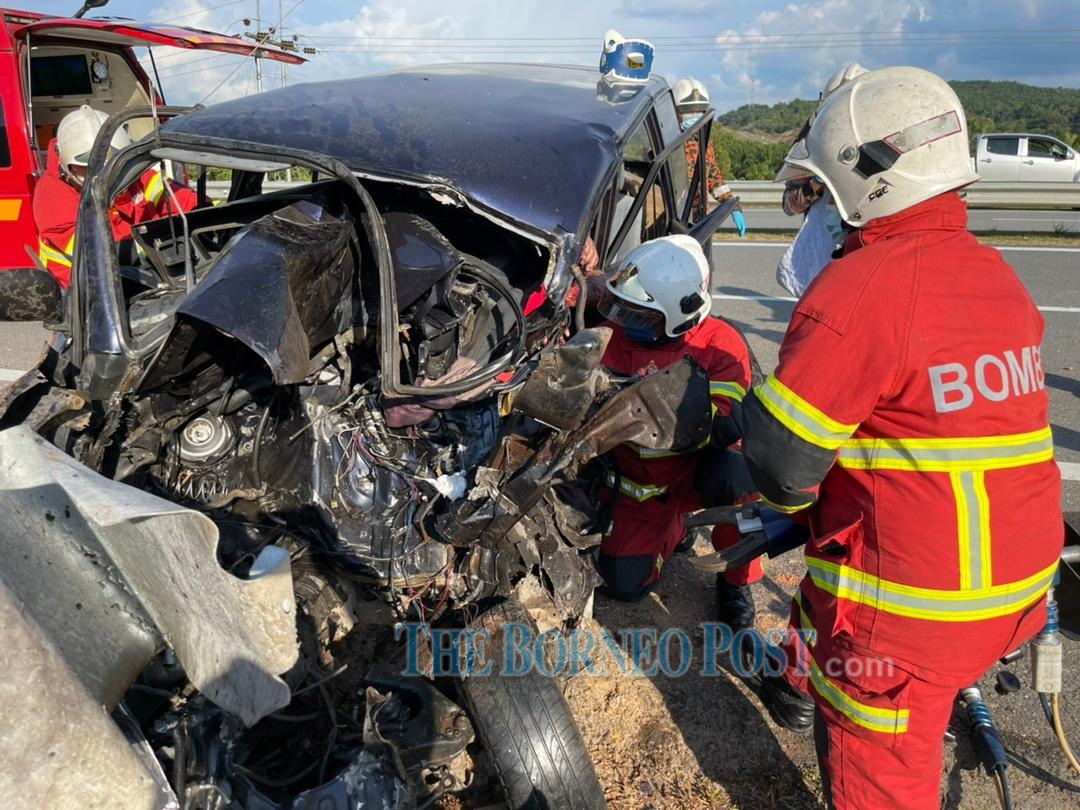 Firefighters working to extricate the passenger from the wreckage. u00e2u20acu2022 Borneo Post pic