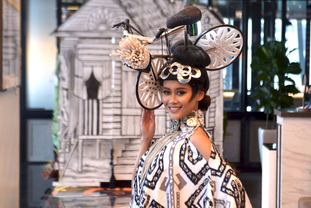 Francisca wears a whimsical headpiece featuring a bicycle as part of the national costume.