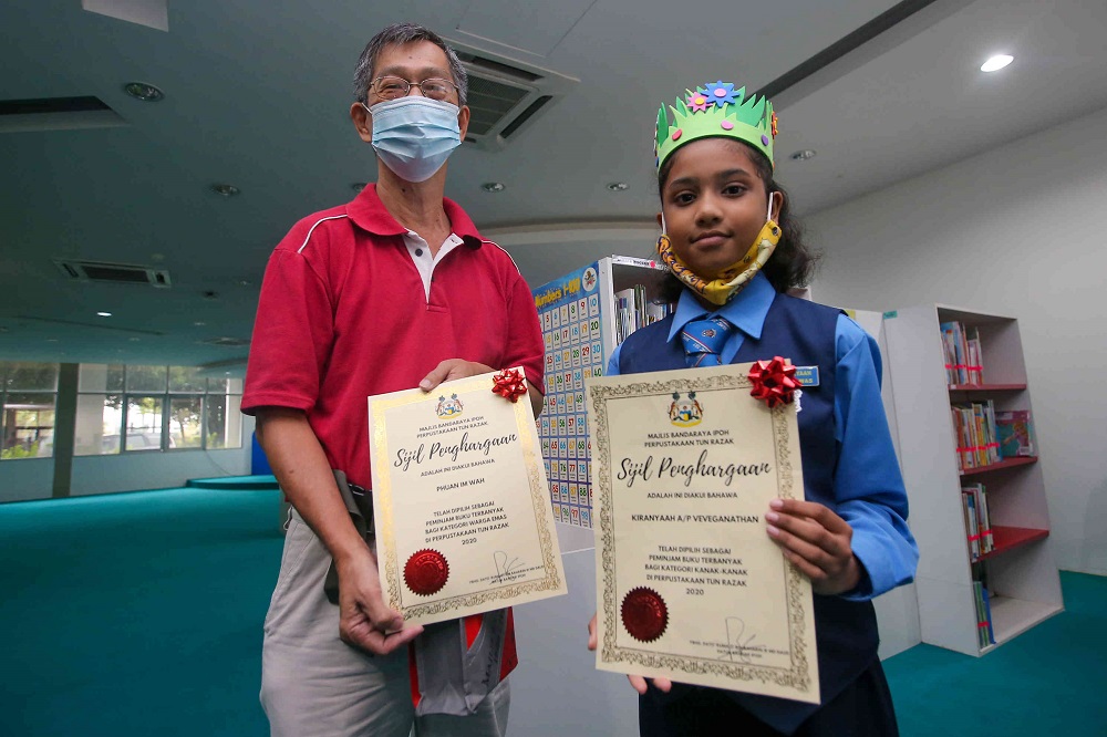 V. Kiranyaah(right) and Phuan Im Wah receiving their awards by Tun Razak Library for their reading habits. 