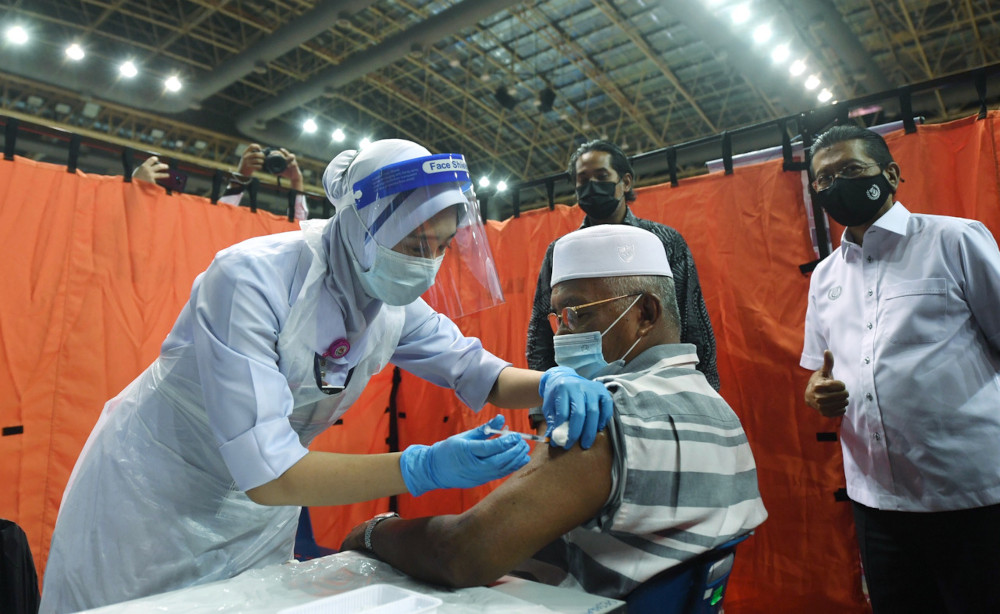 Khairy Jamaluddin watches as Md Jamil Idris, 71, receives his Covid-19 jab at the vaccine dispensing centre at Sultan Abdul Halim Stadium, in Kedah, April 26, 2021. u00e2u20acu201d Bernama pic