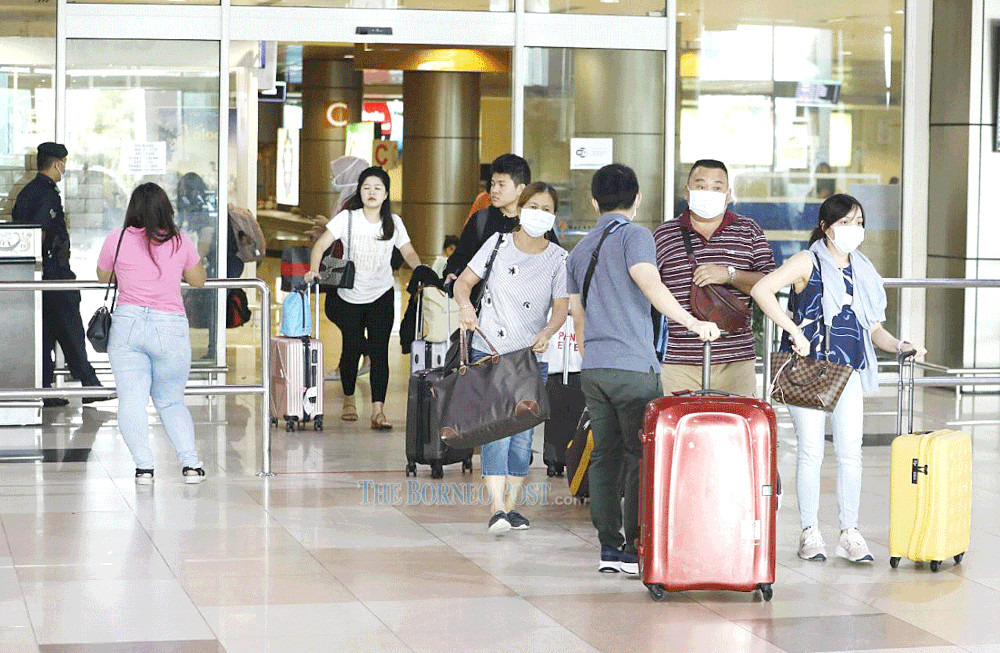 Photo shows several passengers u00e2u20acu201d all of whom are wearing face masks u00e2u20acu201d heading out of the arrival hall at Kuching International Airport. u00e2u20acu201d Borneo Post Online picnn