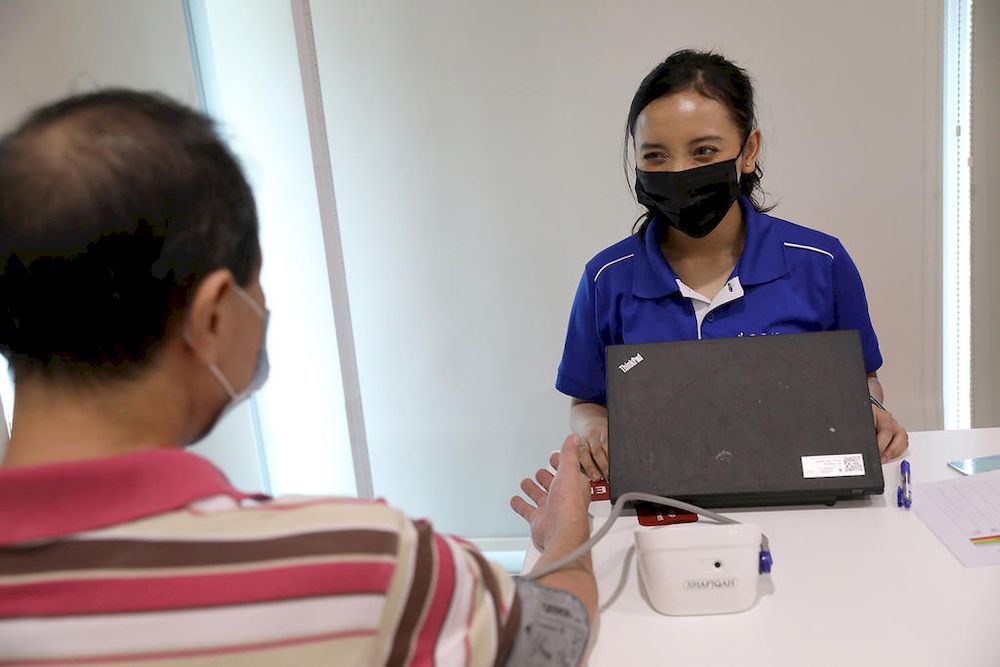 Nurul Shafiqah, Tan Tock Seng Hospital's health coach, checking the blood pressure of a resident in the community she serves. u00e2u20acu201d TODAY pic
