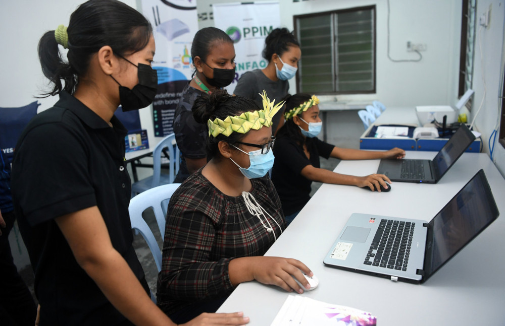 Suzana Tijak (seated, left) and Zurina Sukri surf the internet on laptops after the handing over of the computer lab as part of the Enculturation of ICT Literacy Tour programme, in Kampung Jeram Kedah Ulu Beranang Lenggeng, April 22, 2021. u00e2u20acu201d Bernama pic