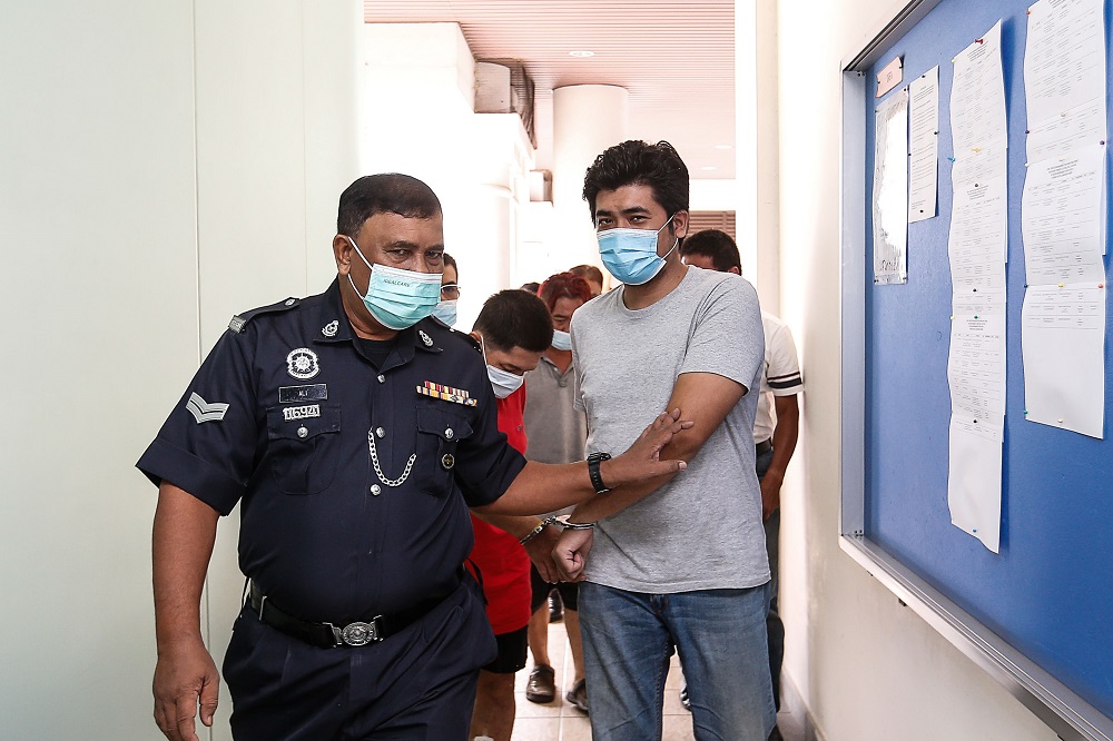 Muhammad Aslam Hashim is escorted by a policeman at the Magistrateu00e2u20acu2122s Court in George Town April 23, 2021. u00e2u20acu2022 Picture by Sayuti Zainudin