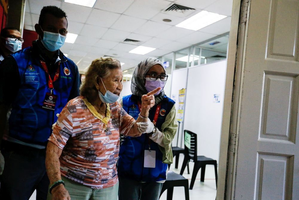 A senior citizen is escorted to receive her Covid-19 shot under phase two of Penangu00e2u20acu2122s immunisation drive at the Caring Society Complex in George Town April 19, 2021. u00e2u20acu201d Picture by Sayuti Zainudinnn