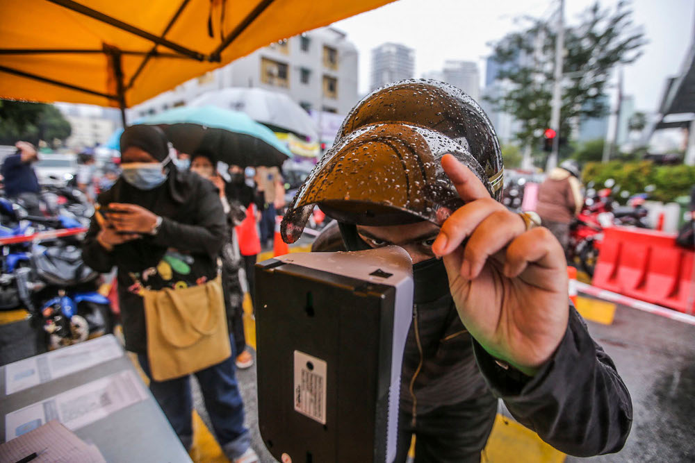 Visitors check their body temperature at the Kampung Baru Ramadan bazaar, April 14, 2021. u00e2u20acu2022 Picture by Hari Anggara