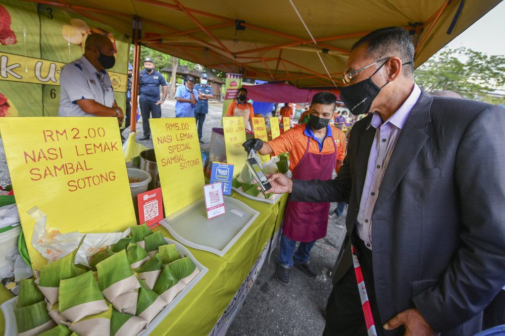 Deputy Domestic Trade and Consumer Affairs Minister Datuk Rosol Wahid scanning the QR code for the e-wallet application to buy u00e2u20acu02dcnasi lemaku00e2u20acu2122 at the Putrajaya farmersu00e2u20acu2122 market, April 6, 2021. u00e2u20acu201d Bernama pic 