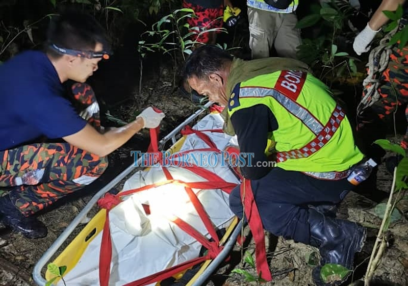 Bomba personnel securing the deceasedu00e2u20acu2122s body on a stretcher before it was brought out of the jungle April 11, 2021. u00e2u20acu201d Borneo Post pic