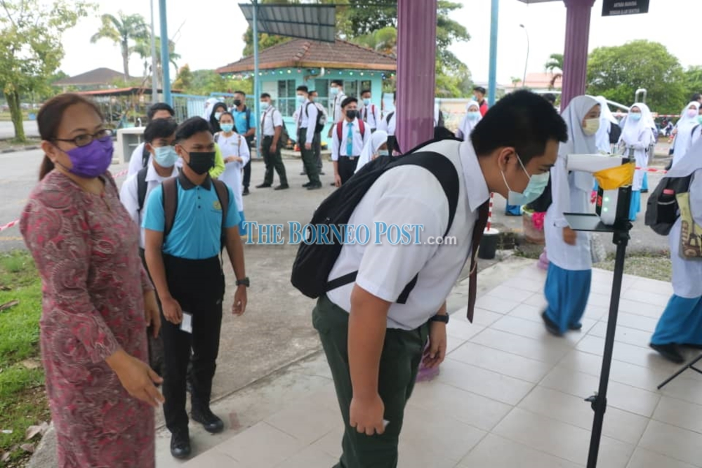 A SMK Kota Samarahan student is seen taking his body temperature before entering the school. u00e2u20acu201d Borneo Post Online pic 