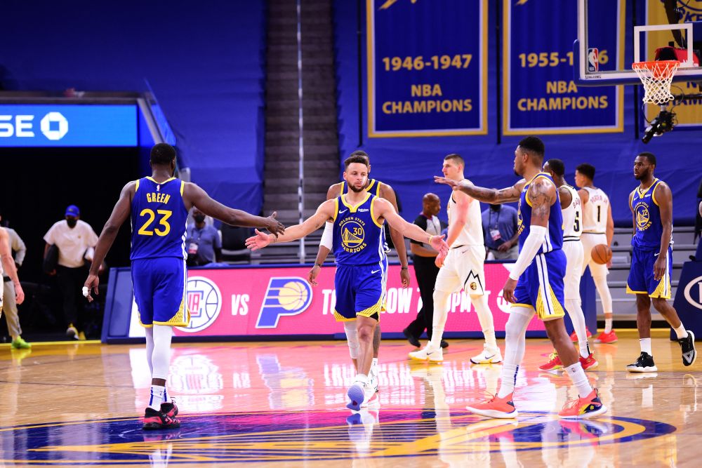 Stephen Curry of the Golden State Warriors high fives Draymond Green #23 and Kent Bazemore #26 during the game against the Denver Nuggets on April 12, 2021 at the Chase Centre in San Francisco. u00e2u20acu201d AFPnn