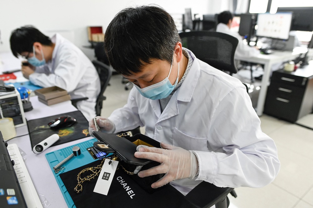 This picture taken on March 24, 2021 shows a staff member verifying the authenticity of a handbag at the Beijing Extraordinary Luxuries Technology company in Beijing. u00e2u20acu201d AFP pic