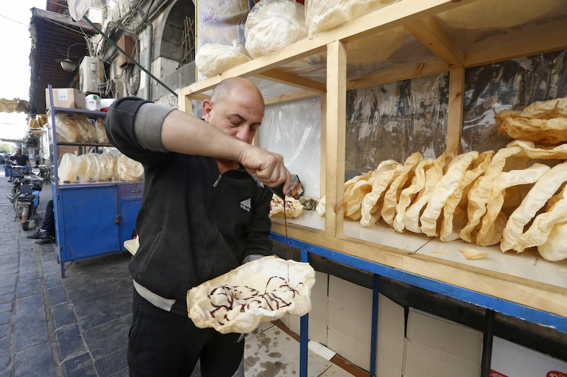 A Syrian vendor spreads grape molasses on a traditional sweet known as u00e2u20acu02dcal-Naemu00e2u20acu2122, commonly served during the Muslim holy month of Ramadan, in Damascus April 28, 2021. u00e2u20acu201d AFP pic
