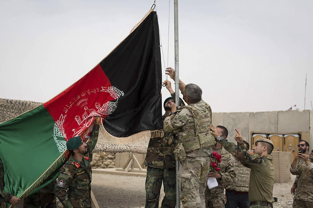 US soldiers and Afghan National Army (ANA) soldiers raise Afghanistan's national flag during a handover ceremony to the ANA army 215 Maiwand corps at Antonik camp in Helmand province May 2, 2021. u00e2u20acu201d Afghanistan Ministry of Defence handout via AFP