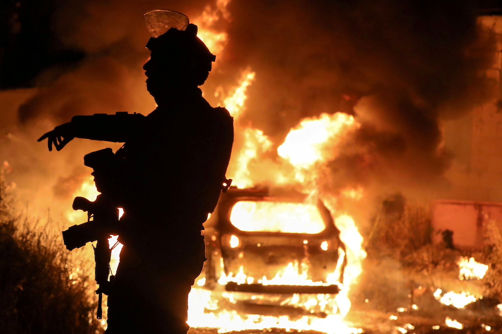 An Israeli policeman gestures as a car belonging to Jewish settlers burns amid tension over the possible eviction of several Palestinian families from homes on land claimed by Jewish settlers in East Jerusalem, May 6, 2021. u00e2u20acu201d Reuters pic