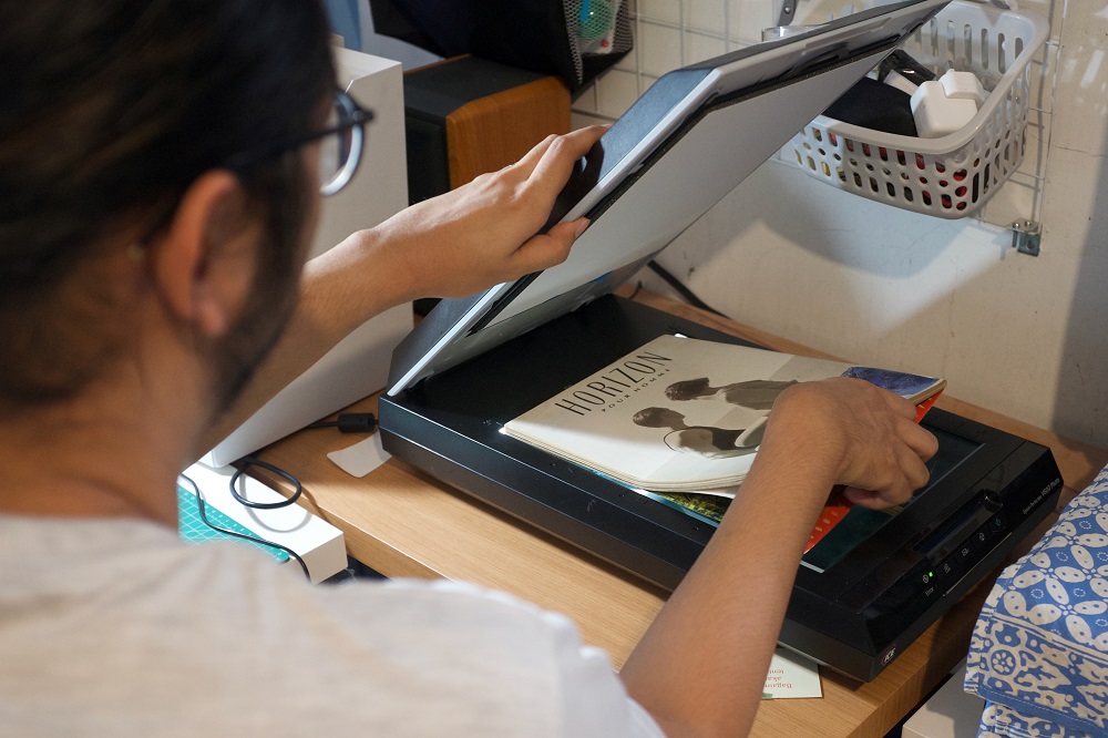 Ais, a 29-year-old LGBT+ researcher, puts a copy of Indonesiau00e2u20acu2122s decades-old LGBT+ magazine on a scanner while digitising it in Jakarta May 8, 2021. u00e2u20acu201d Picture courtesy of Ais/Handout via Reuters