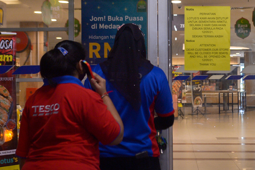 Workers are seen outside the entrance as malls are closed from May 9-11 as part of HIDE requirement during MCO 3.0 at Lotus Setia Alam May 9, 2021. — Picture by Miera Zulyana
