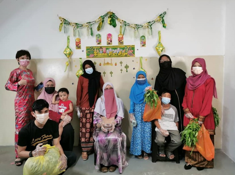 Tan (far left) and Norhayati (seated) with her eight children who were happy after selecting their favourite Hari Raya clothes. u00e2u20acu201d Picture via Nicole Tan Lee Koon 