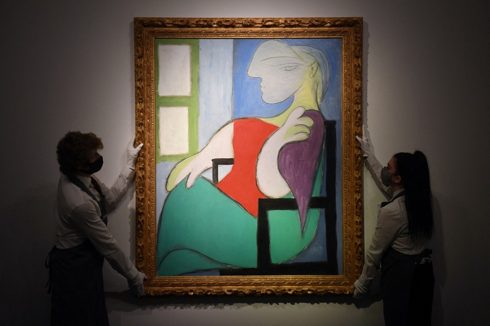 Gallery workers display an artwork titled u00e2u20acu02dcWoman sitting by a window (Marie-Therese)u00e2u20acu2122 at Christie's in New York April 22, 2021. u00e2u20acu201d AFP pic