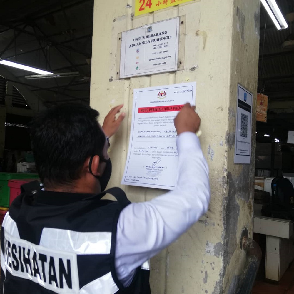 A health department personnel putting up a notice on the closure of the market. — Picture courtesy of MBPP