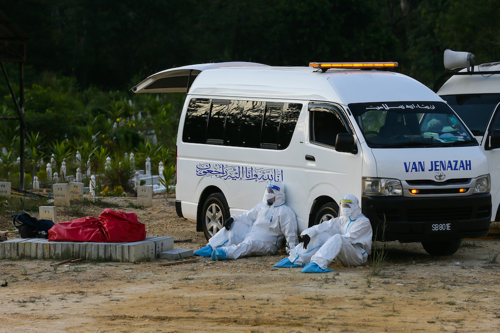 Covid 19 victims body arrive for funeral service handled by health workers equiped with personal protective suit at Kampung Sungai Pusu muslim cemetery.Health workers are seen lean to the van while take a break May 22,2021. u00e2u20acu201d Picture by Ahmad Zamzahuri