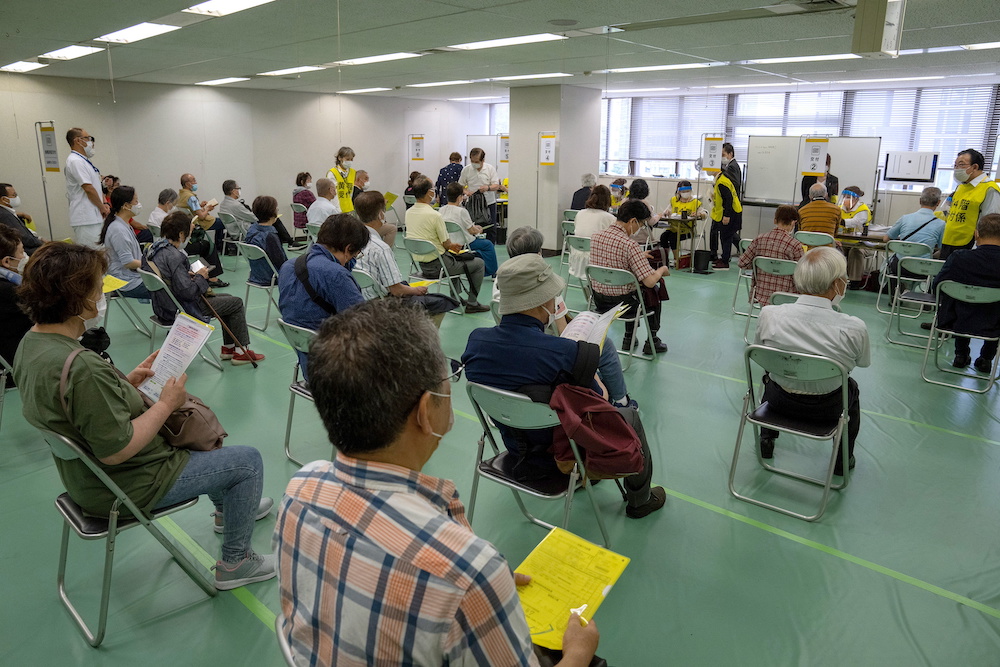 People wait to be processed after arriving to receive the Moderna Covid-19 vaccine at the newly-opened mass vaccination centre in Tokyo, Japan, May 24, 2021. u00e2u20acu201d Carl Court/Pool via Reuters