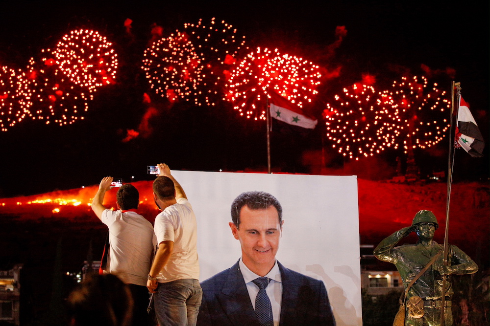 A poster depicting Syriau00e2u20acu2122s president Bashar al-Assad is seen as supporters of him celebrate after the results of the presidential election announced that he won a fourth term in office, in Damascus, Syria May 27, 2021. u00e2u20acu201d Reuters pic