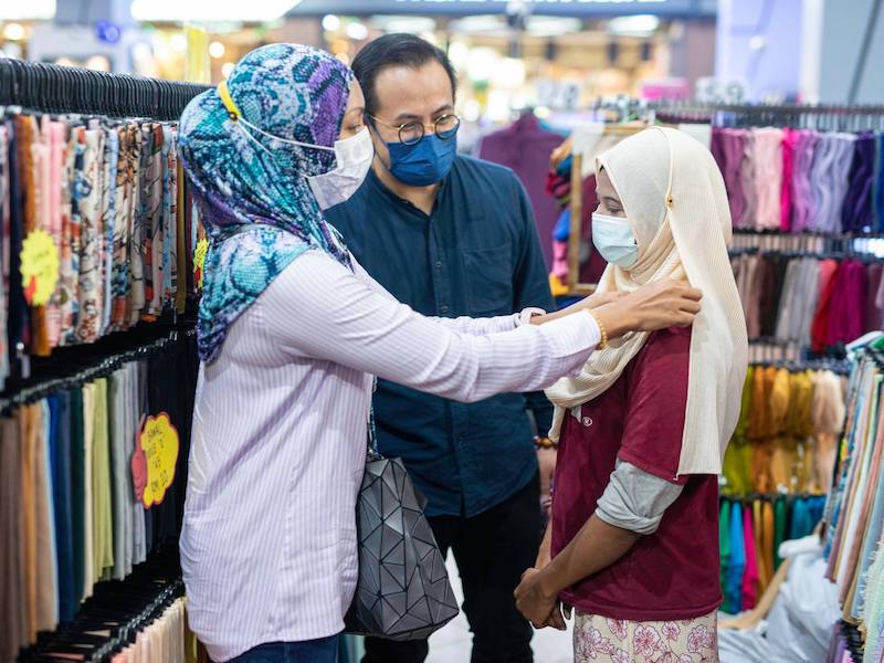 A female shopper helps Siti with her new tudung. — Picture from Facebook/Steven Sim