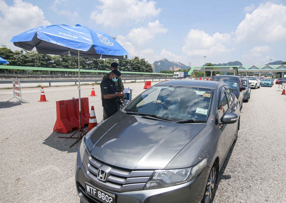 Police personnel conduct checks on vehicles at a roadblock during MCO 3.0 at the Ipoh Selatan Toll May 10, 2021. u00e2u20acu201d Picture by Farhan Najib