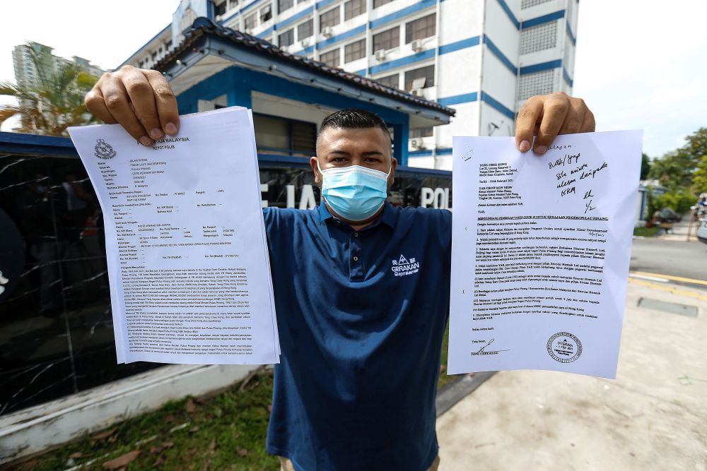 Penang Gerakan Youthu00e2u20acu2122s Mohd Aswaad Jaafar holds up a police report on the bogus Covid-19 vaccine donation drive at the Northeast District police station May 20, 2021. u00e2u20acu2022 Picture by Sayuti Zainudin