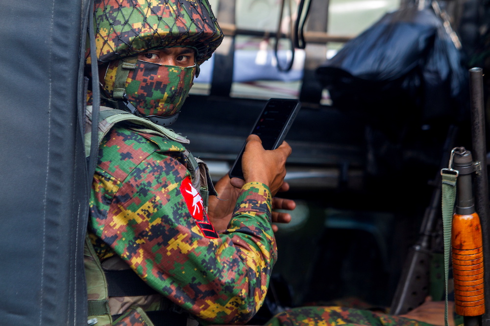 A soldier uses a mobile phone as he sit inside a military vehicle outside Myanmaru00e2u20acu2122s Central Bank during a protest against the military coup, in Yangon, Myanmar, February 15, 2021. u00e2u20acu2022 Reuters picnnnn