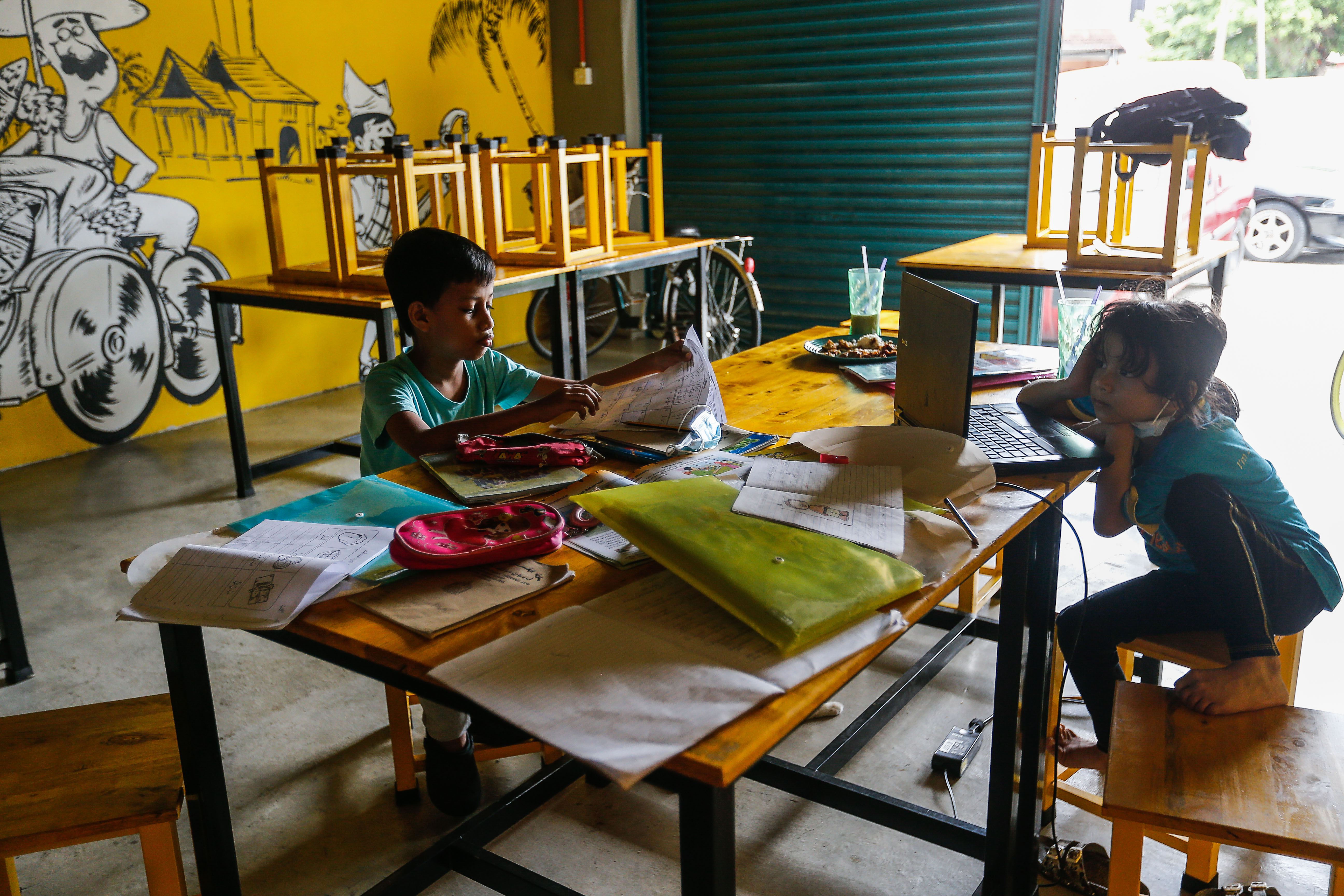 Shamsul Munir Safini's son Aisy Affan and daughter Alya Shamsul Munir focus on their homework while he runs his restaurant in Hala Kalui, Seberang Jaya May 17, 2021. u00e2u20acu201d Picture by Sayuti Zainudin