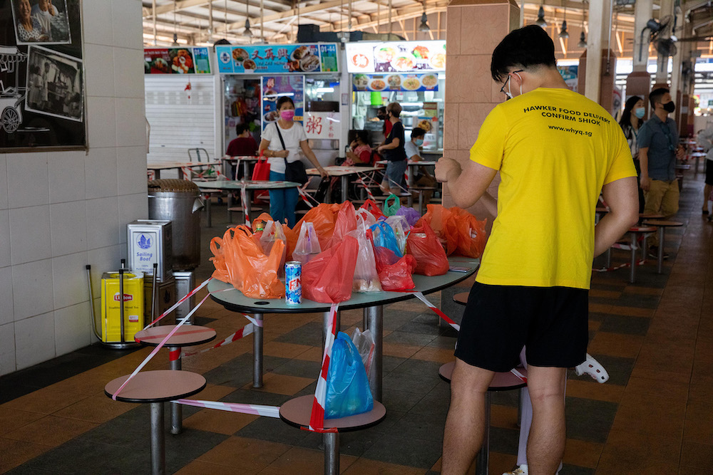 A WhyQ hawker food delivery staff sorting out takeaway orders at Ghim Moh Hawker Centre on May 28, 2021. The older generation of hawkers must grapple with the changing habits of their customers, especially the younger ones, who are now getting used to hav