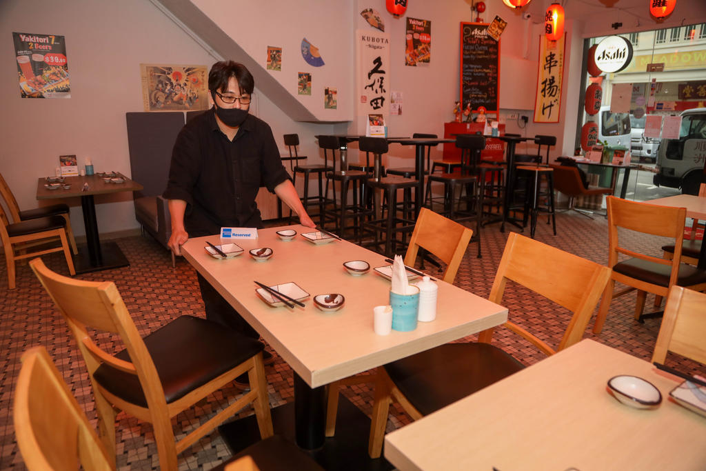 A worker at Hinode Izakaya and Bar separating tables that would normally seat up to eight. u00e2u20acu2022 TODAY pic
