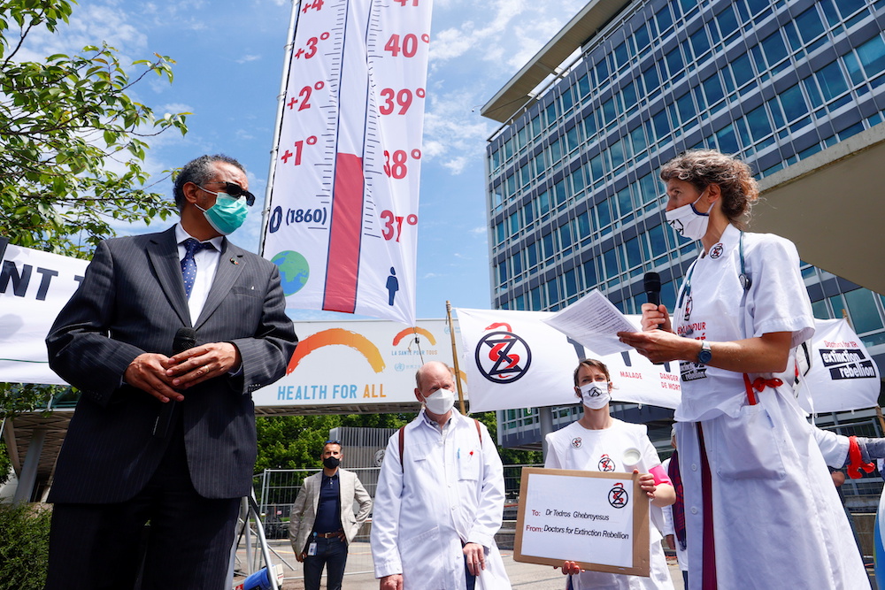 World Health Organization (WHO) Director General Tedros Adhanom Ghebreyesus holds a microphone as members of Doctors for XR (Extinction Rebellion) present him with a letter urging him to take action on climate change, in Geneva, Switzerland, May 29, 2021.