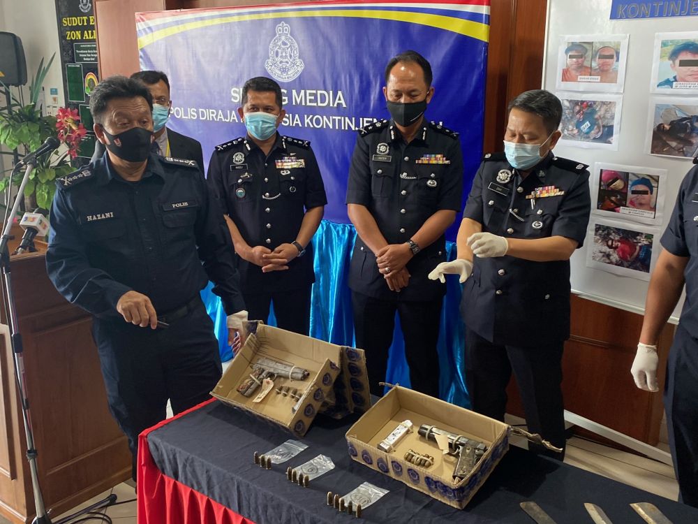 Sabah police commissioner Datuk Hazani Ghazali (left) shows the pistols used by the suspects in the shootout yesterday morning. u00e2u20acu201d Picture by Julia Channn