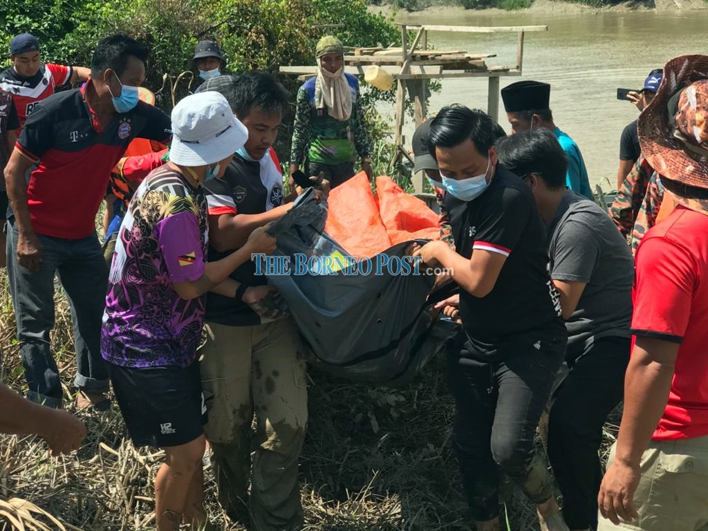 The body of the victim is carried to the riverbank. u00e2u20acu2022 Borneo Post pic