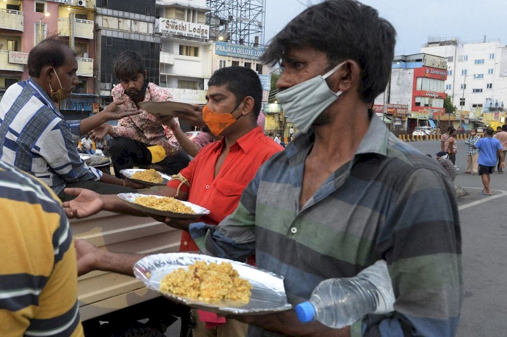 Volunteers of an non-governmental organisation (NGO) distribute food to people waiting to return home outside at a railway station during a lockdown to curb the spread of Covid-19 in Secunderabad, the twin city of Hyderabad on May 29, 2021. u00e2u20acu201d AFP pic