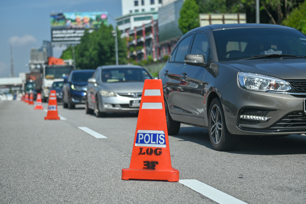 Police officers conducting roadblock checks during movement control order 3.0 (MCO) on the Federal Highway May 10, 2021. u00e2u20acu201d Picture by Miera Zulyana