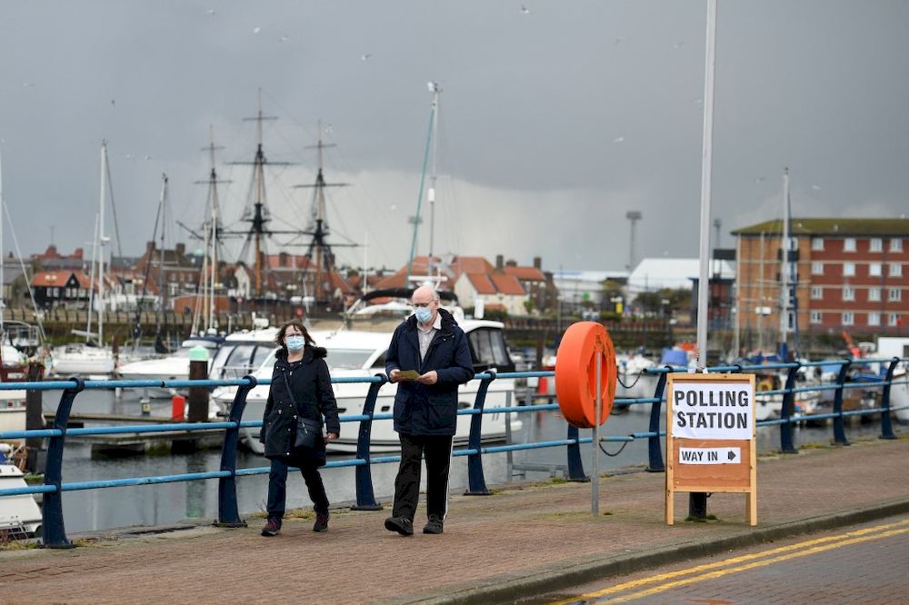 A couple wearing protective face coverings to combat the spread of the coronavirus, walk past a sign for a Polling Station beside the marina in Hartlepool, north-east England on May 6, 2021. u00e2u20acu201d AFP pic