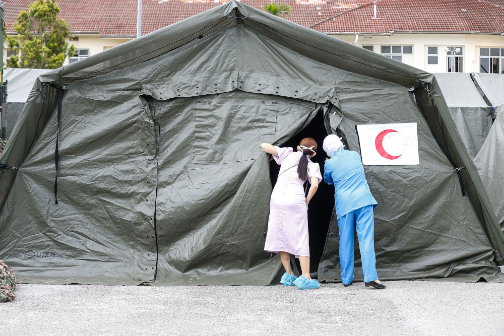 A nurse and a doctor take a peek into one of the ICU tents as they set up Field ICU at Kepala Batas Hospital, May 21, 2021. u00e2u20acu201d Picture by Sayuti Zainudin