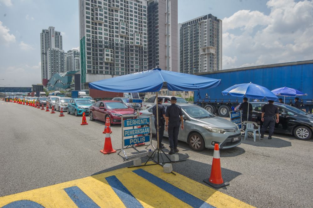 Police personnel conduct checks on vehicles at a roadblock at the KL-Seremban Highway in Kuala Lumpur May 25, 2021. u00e2u20acu201d Picture by Shafwan Zaidonnn