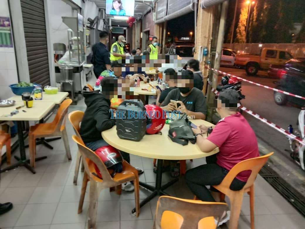 File photo shows police personnel checking on a coffee shop in Kuching for SOP compliance. u00e2u20acu2022 Borneo Post pic