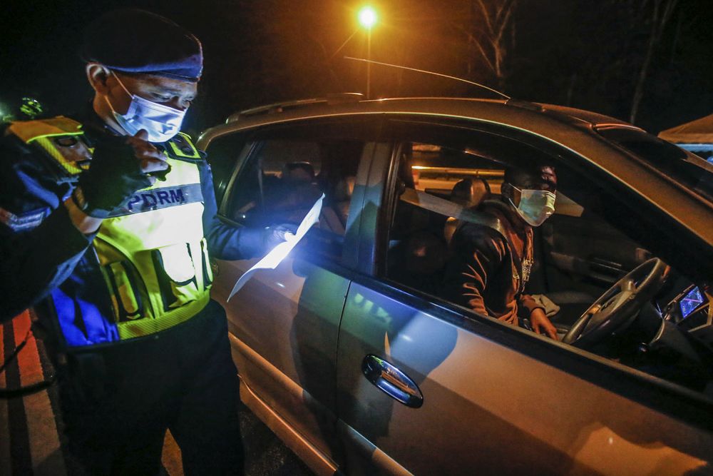 A police personnel checks a driver's travel documents at the Gombak Toll Plaza, Selangor May 5, 2021. u00e2u20acu201d Picture by Hari Anggara