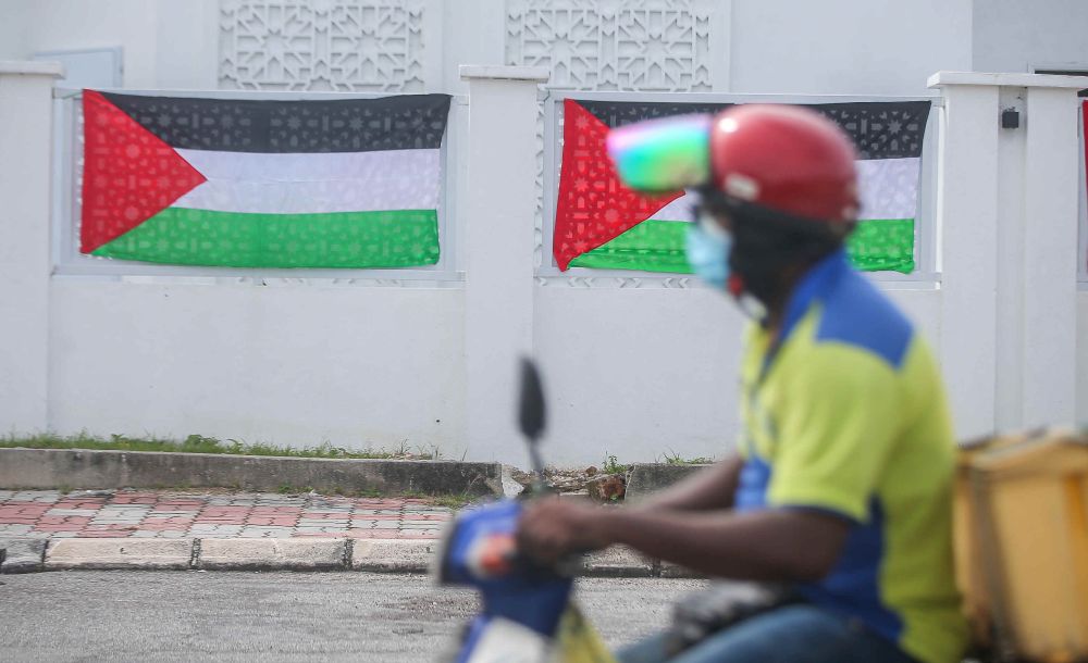 A motorist drives past Palestinian flags seen on the exterior walls of Masjid Jamek Idris Iskandar Shah in Ipoh on May 18, 2021. — Picture by Farhan Najib